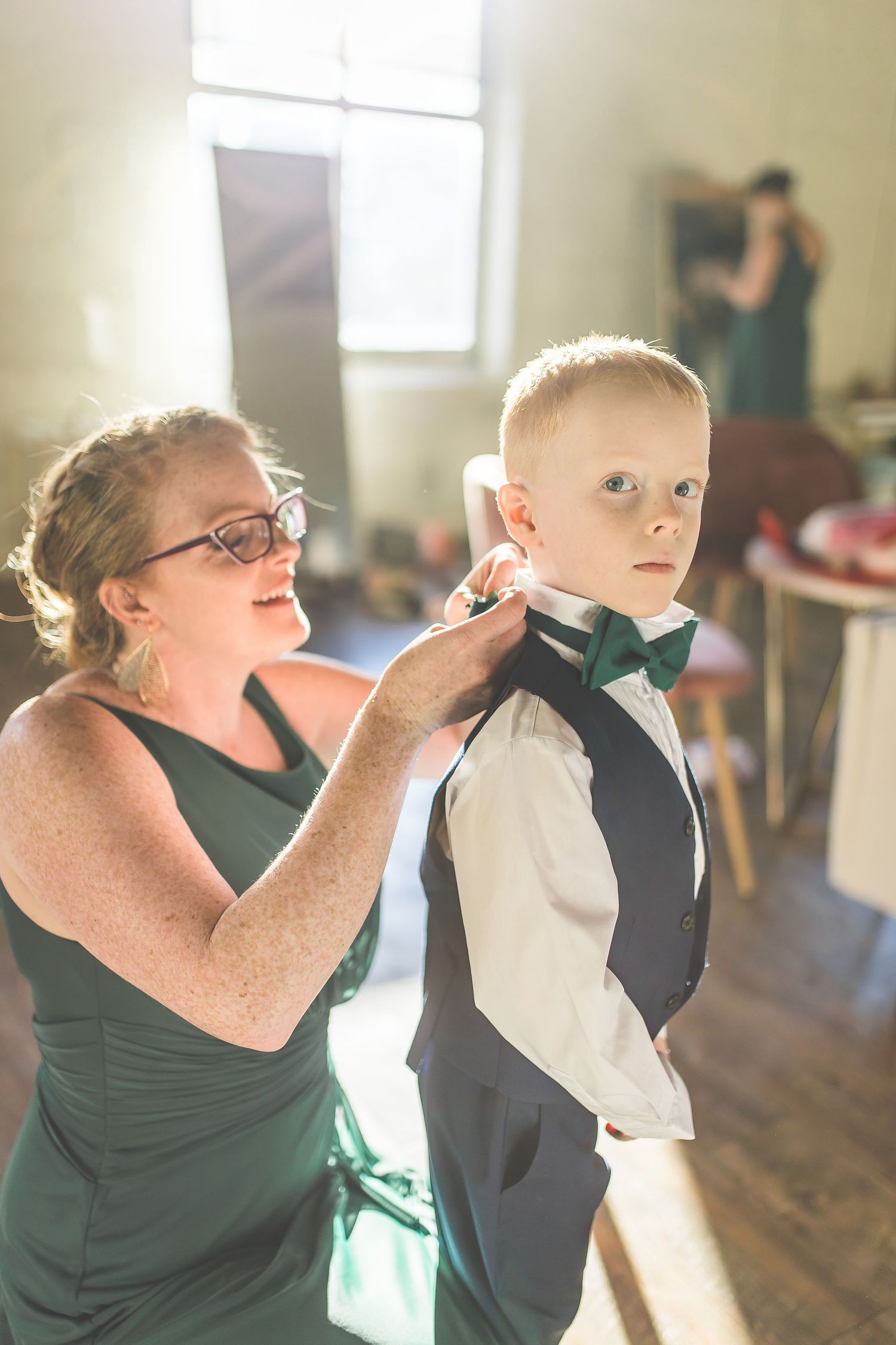 Wedding preparation scene with people in dark green attire helping with final touches.