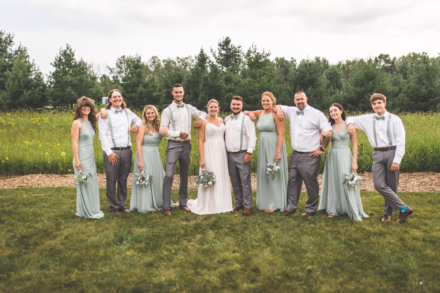 Wedding party lined up in casual poses wearing coordinated blue and white outfits outdoors.