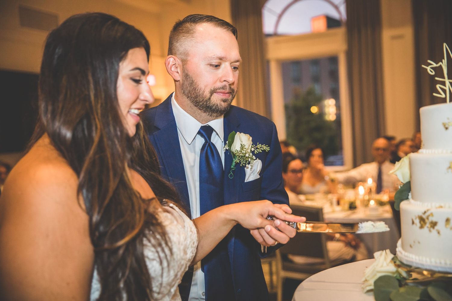 Intimate moment shared during wedding cake cutting ceremony.