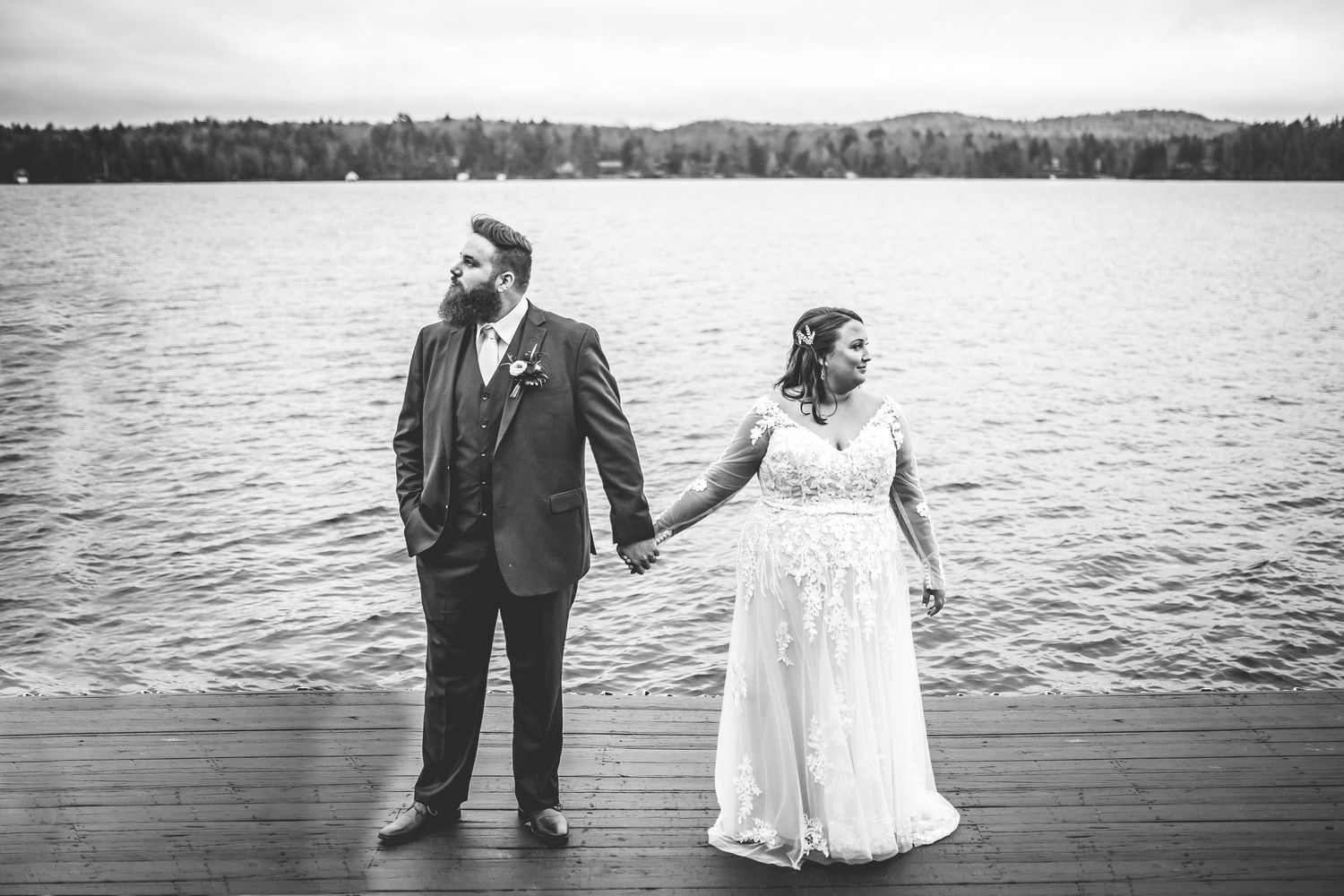 Black and white wedding photos captured on a dock with a lake and mountain backdrop.