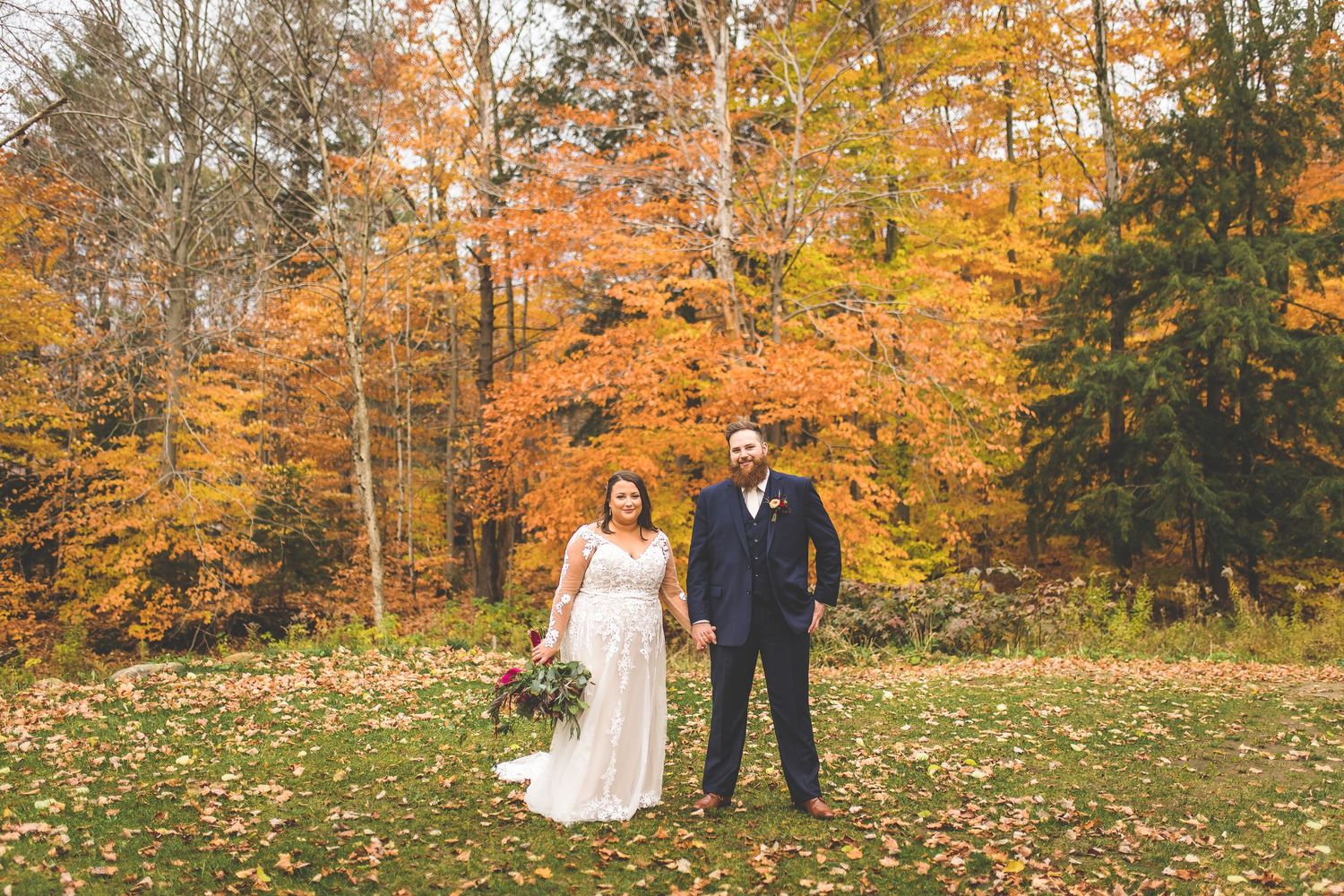 Wedding couple and party pose in a scenic autumn forest setting.
