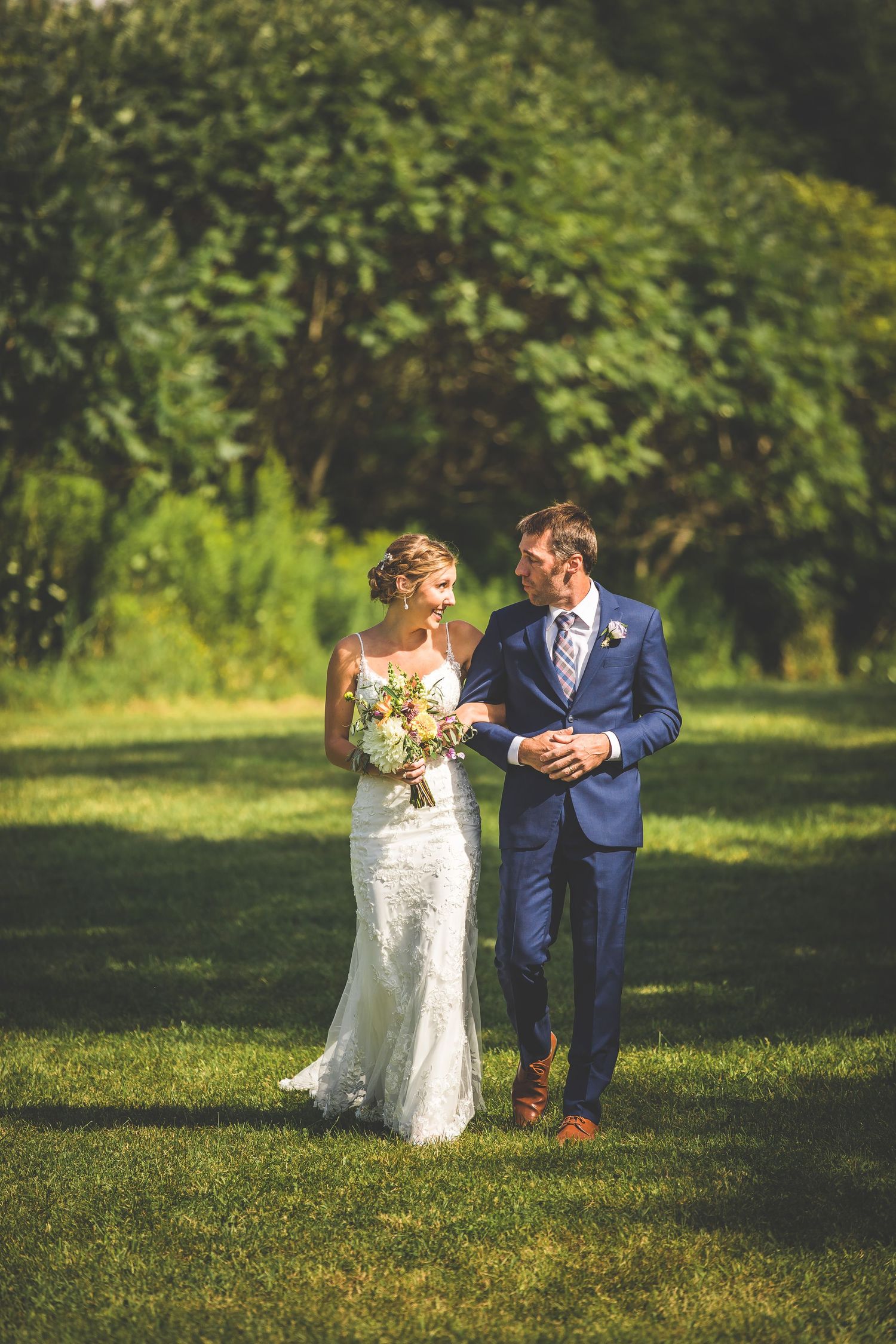A couple shares a romantic moment on a grassy lawn during their wedding day.