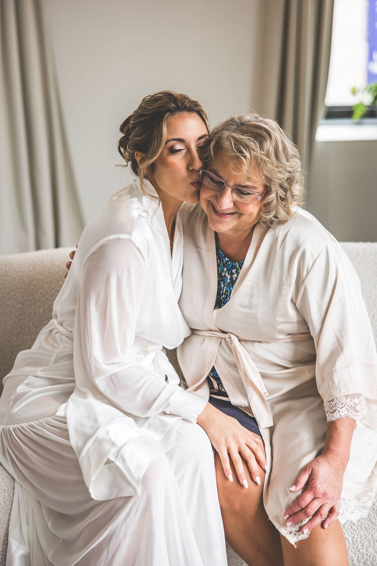 Intimate moment captured during wedding morning preparations in white robes.
