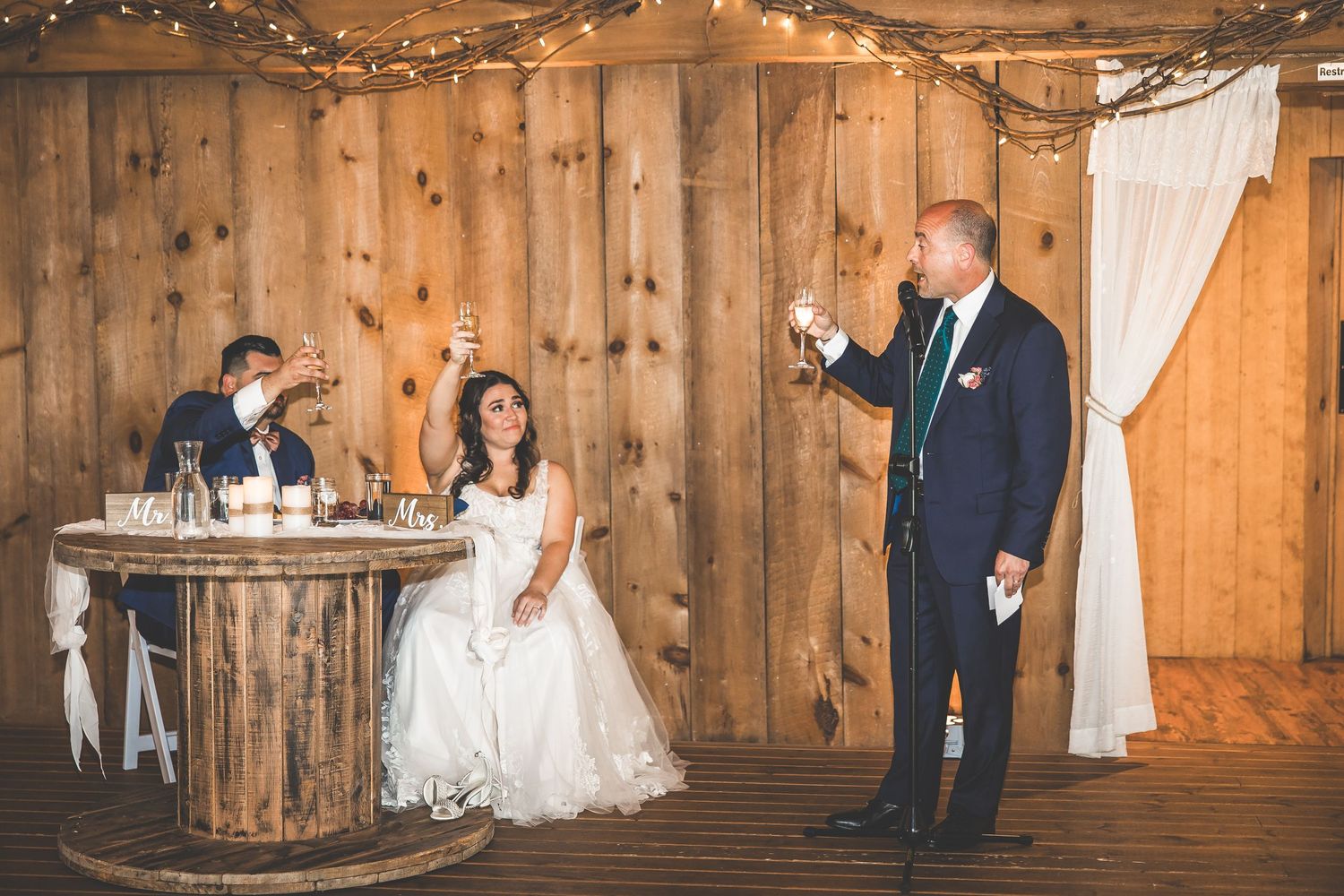 Wedding reception sequence showing romantic moments in a barn with string lights.