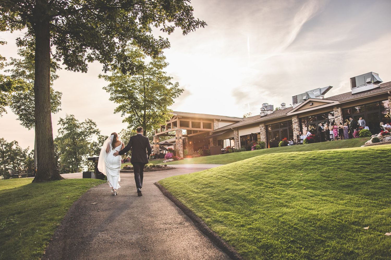 Wedding party walking along a scenic hillside path during golden hour.