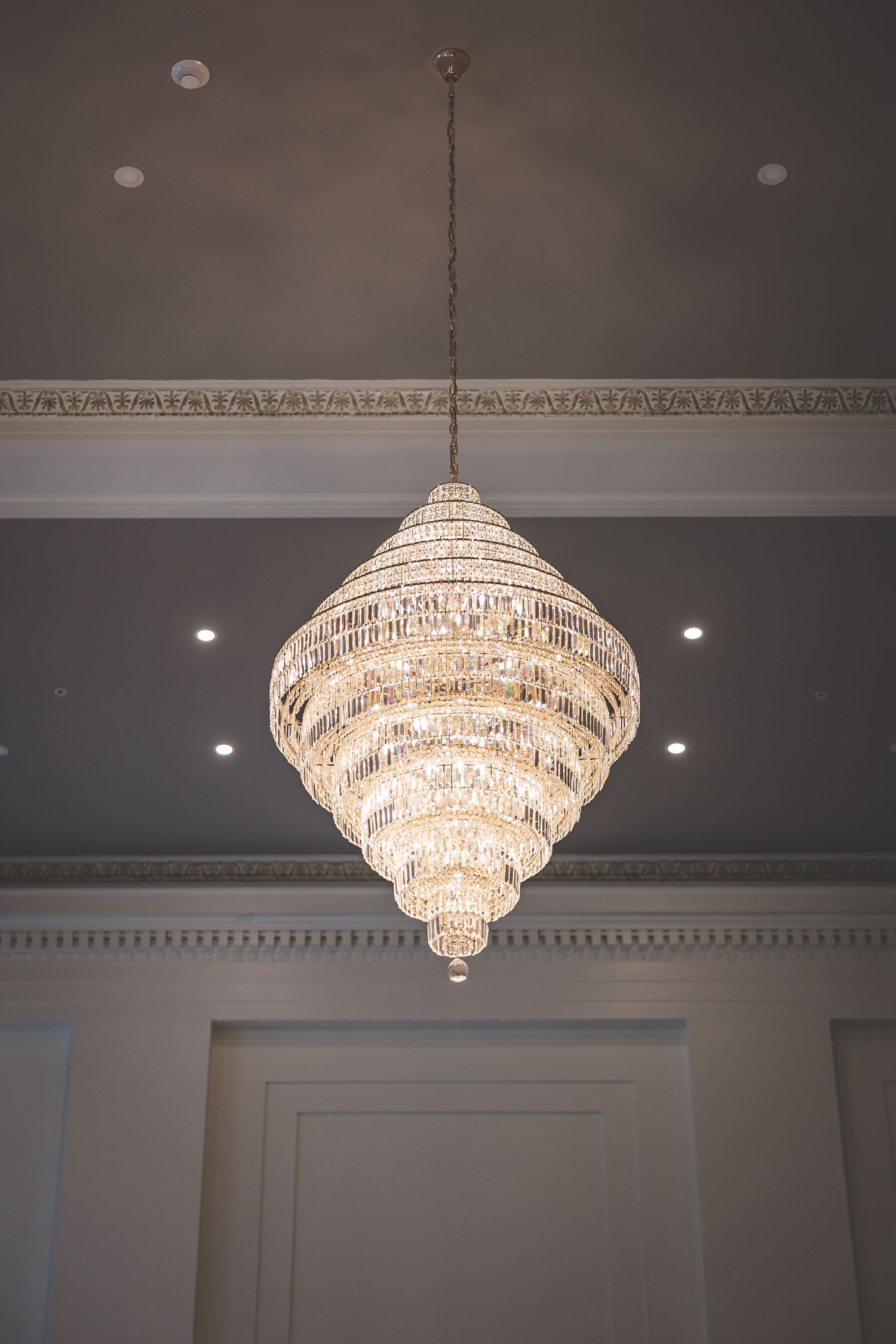 Crystal chandeliers hanging from an ornate ceiling in a luxurious ballroom.