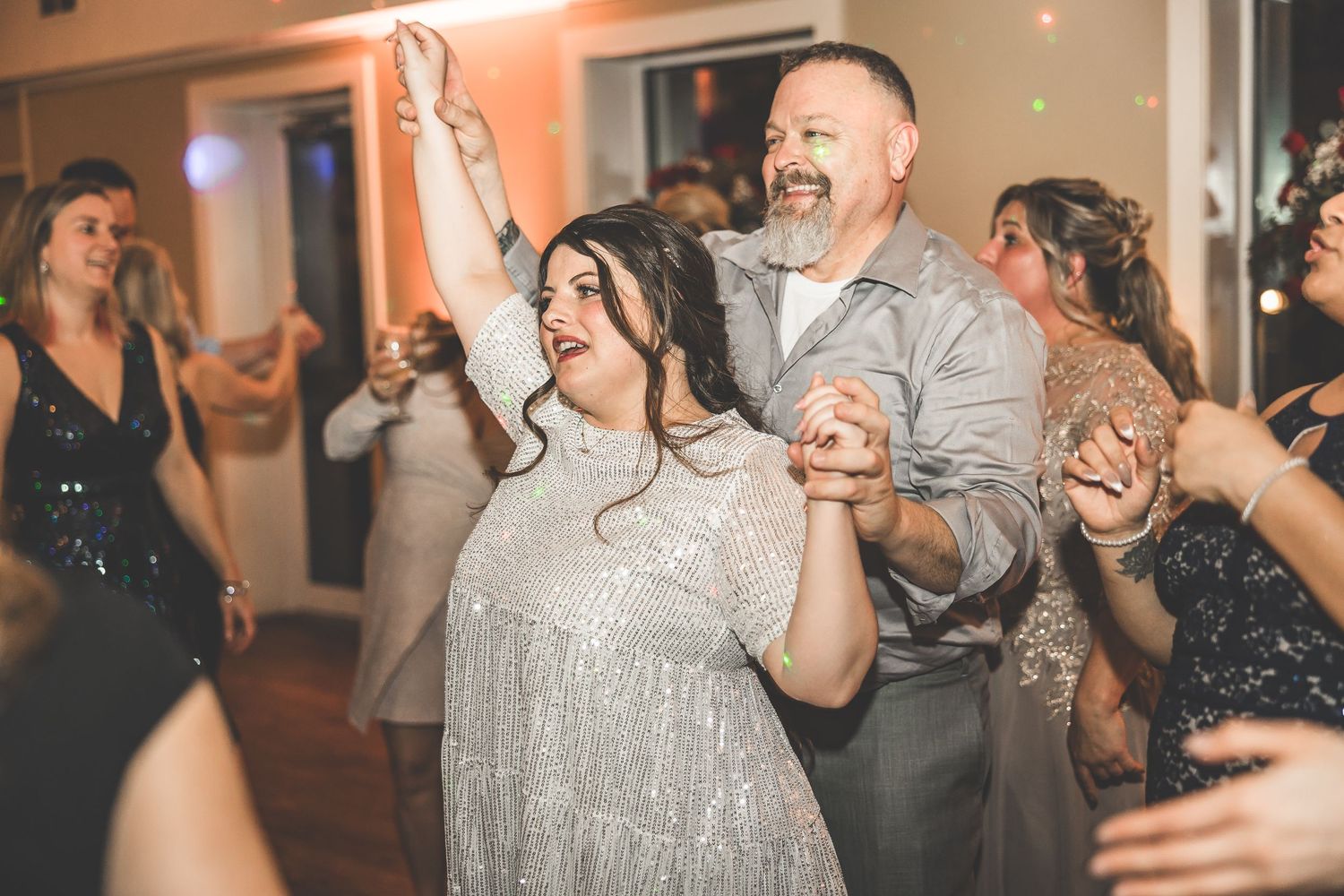 Joyful celebration on dance floor with guests in evening attire.