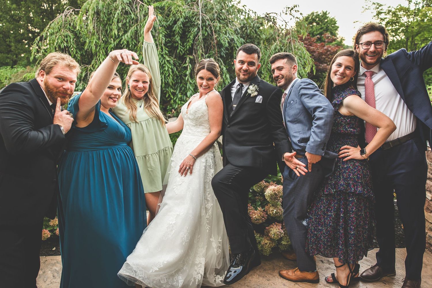 Wedding party poses together outdoors in blue and neutral attire.