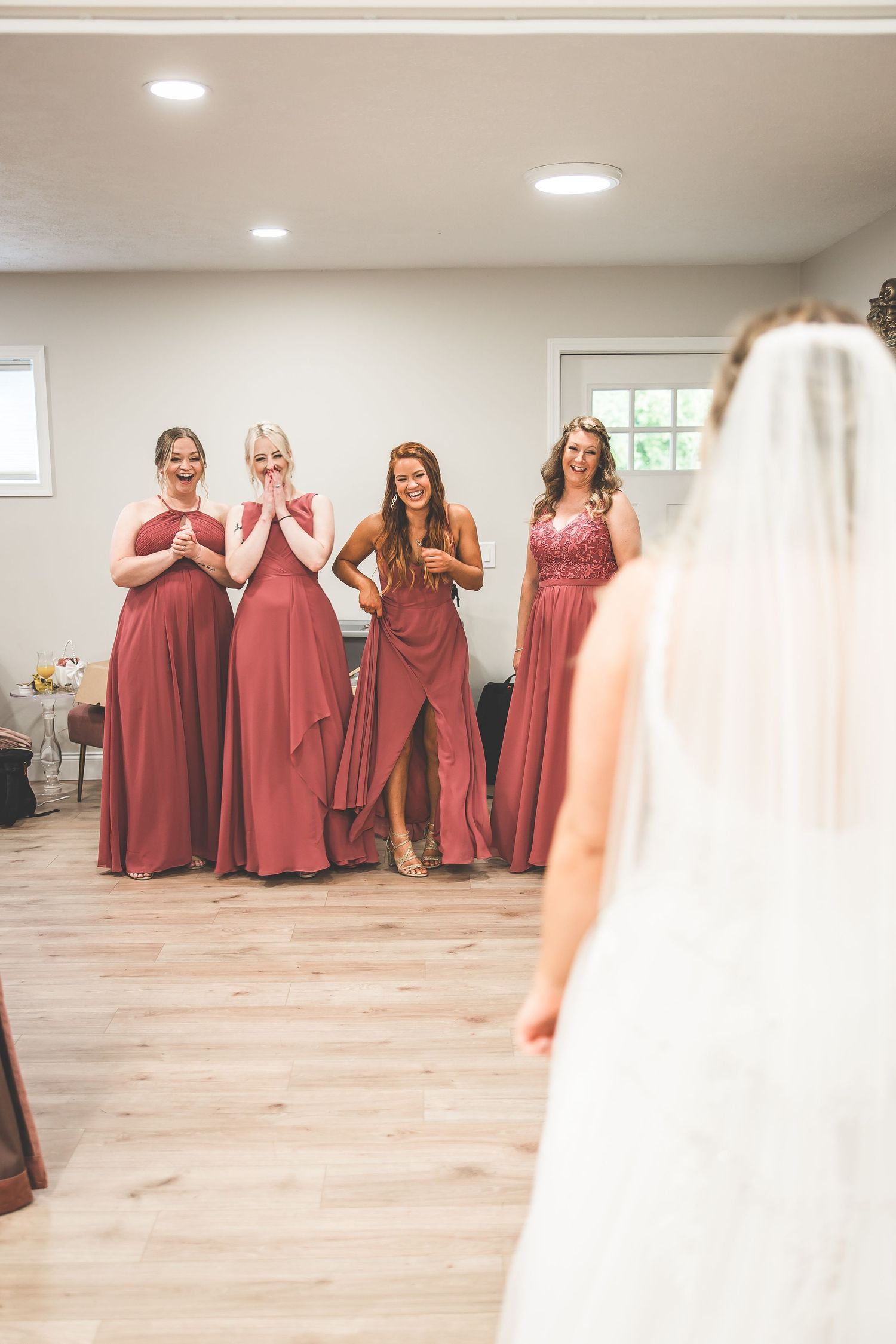 Bridesmaids in dusty rose dresses react emotionally to seeing the bride.