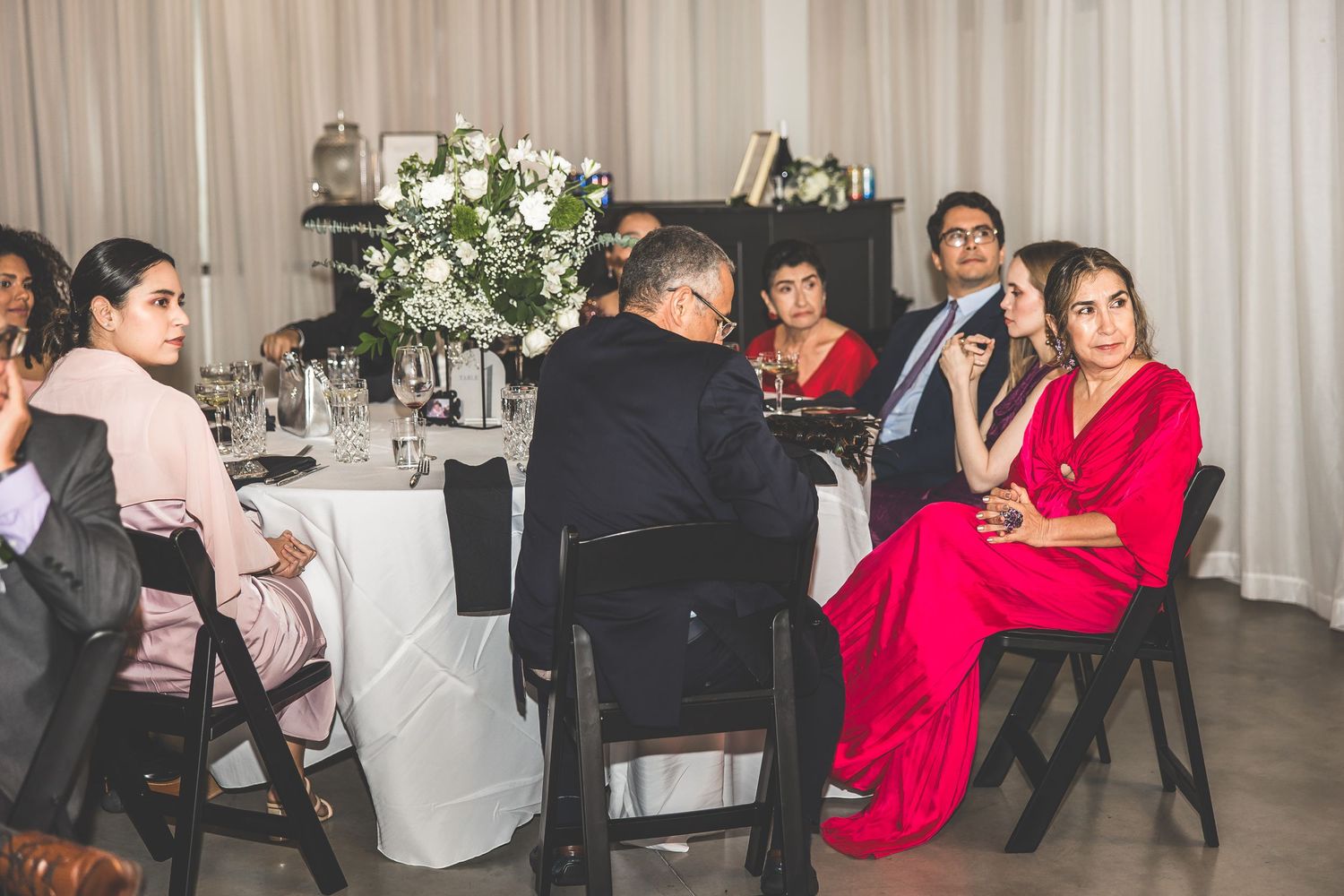 Wedding reception celebration with guests mingling in a white-draped venue space.