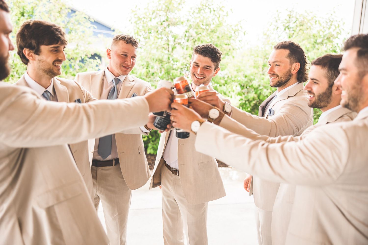 Wedding party in cream suits toasting and celebrating together.