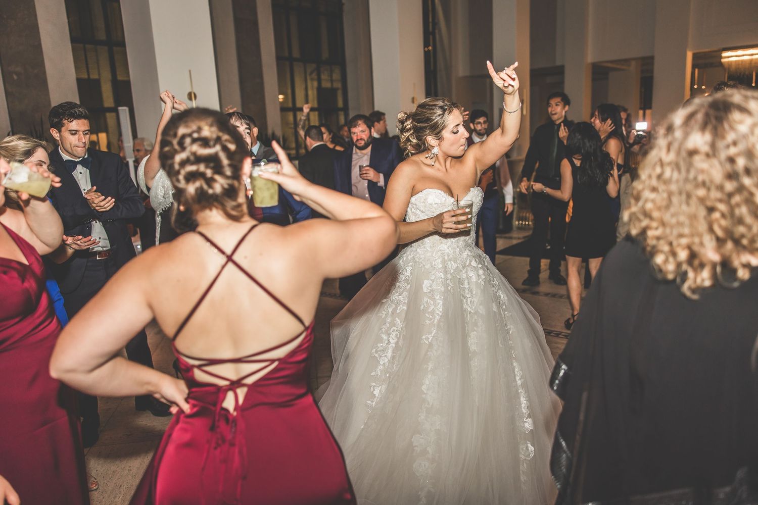 Wedding guests in formal attire dancing and celebrating at an indoor reception venue.