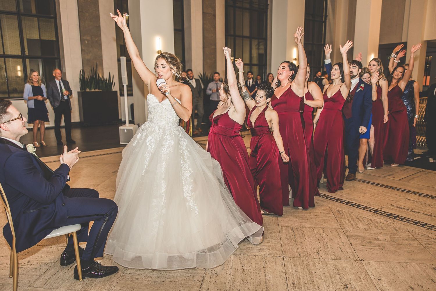 Wedding party strikes dramatic pose during choreographed dance performance at reception.