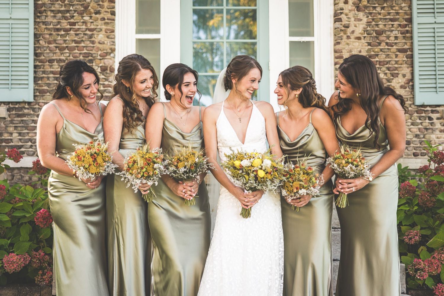 A candid moment of bridesmaids in silk gowns sharing laughter with the bride.