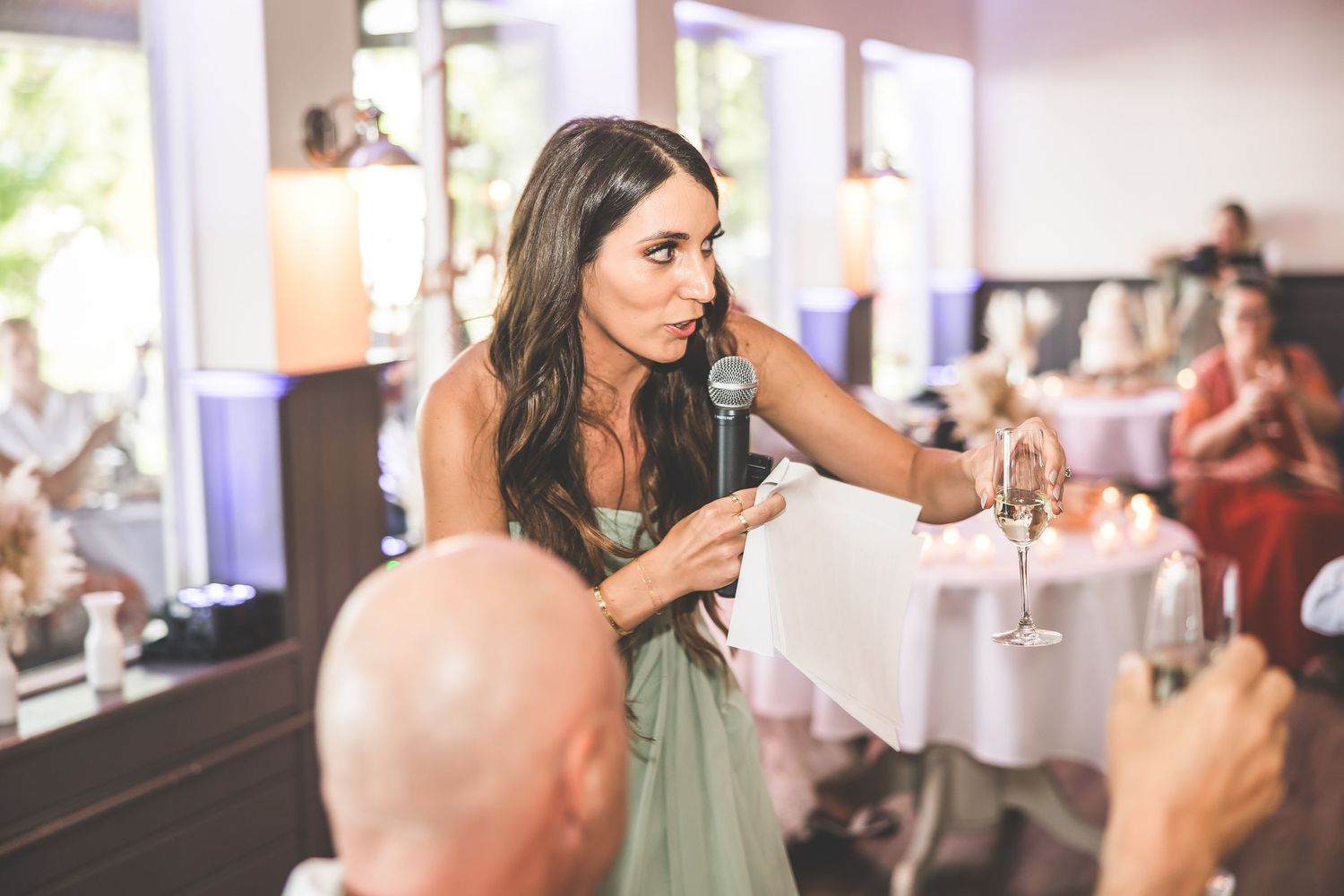 Wedding reception speech being given in elegant venue with natural lighting.