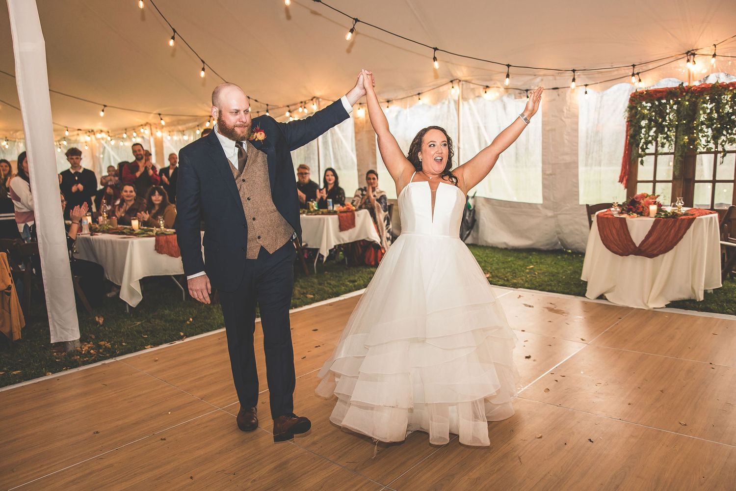 Newlyweds share an intimate dance moment under string lights in a white tent reception.