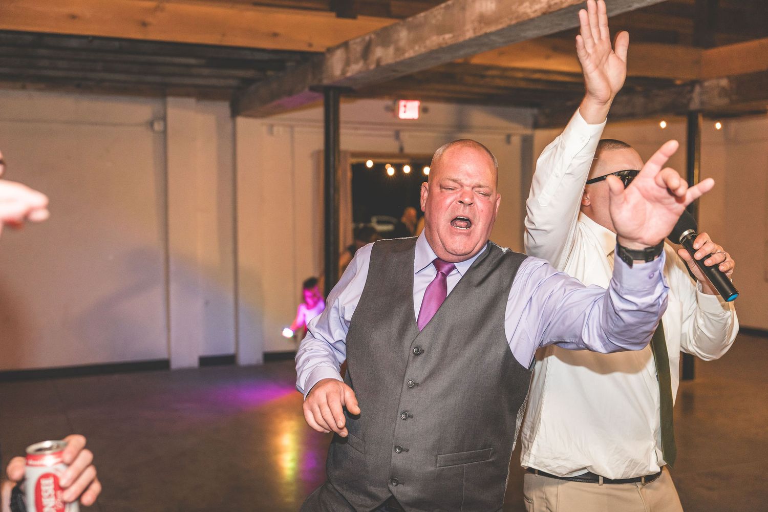 Wedding reception dance floor with guests celebrating and raising their hands.