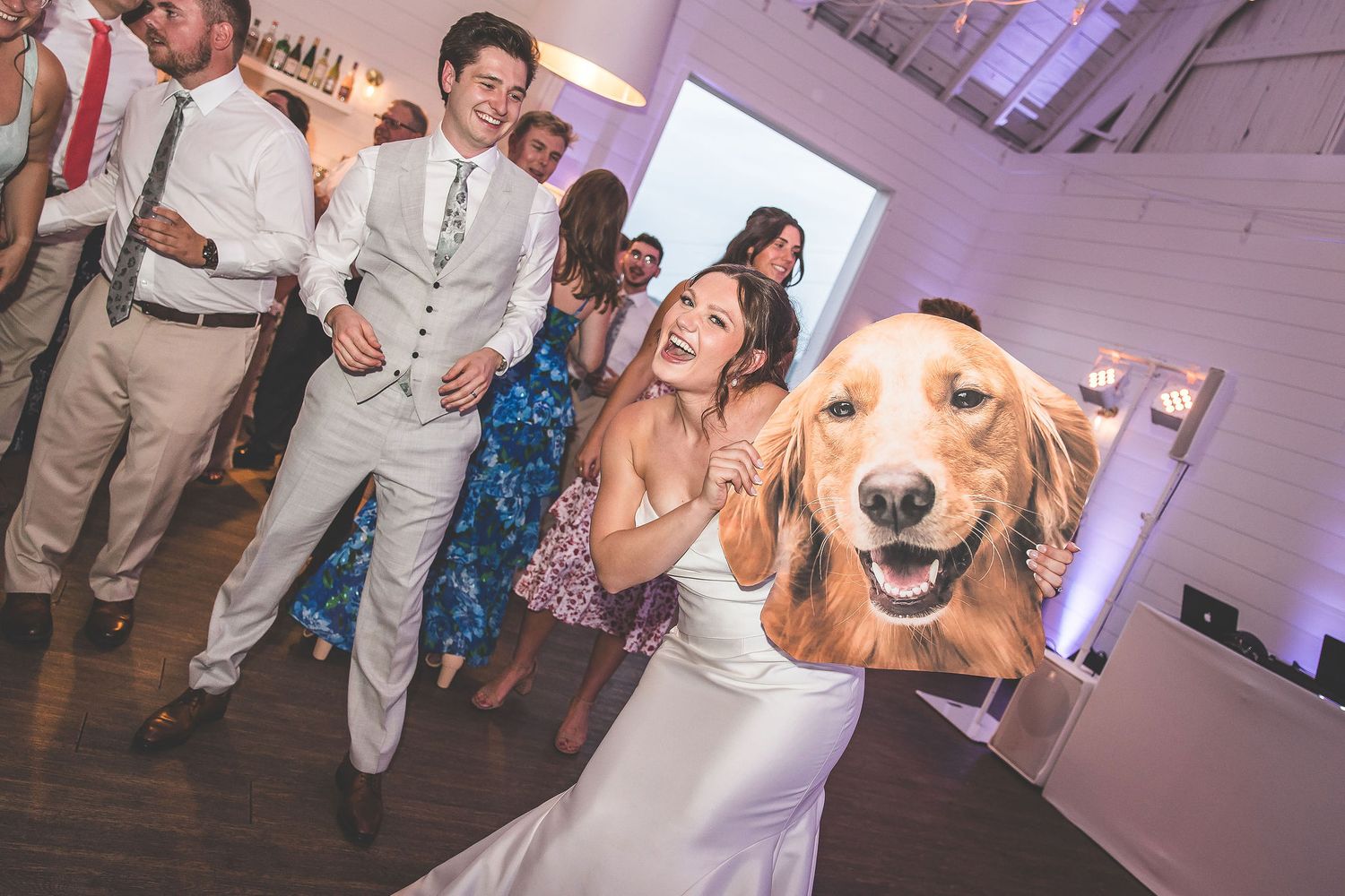 A happy golden retriever photobombs a wedding reception photo on the dance floor.