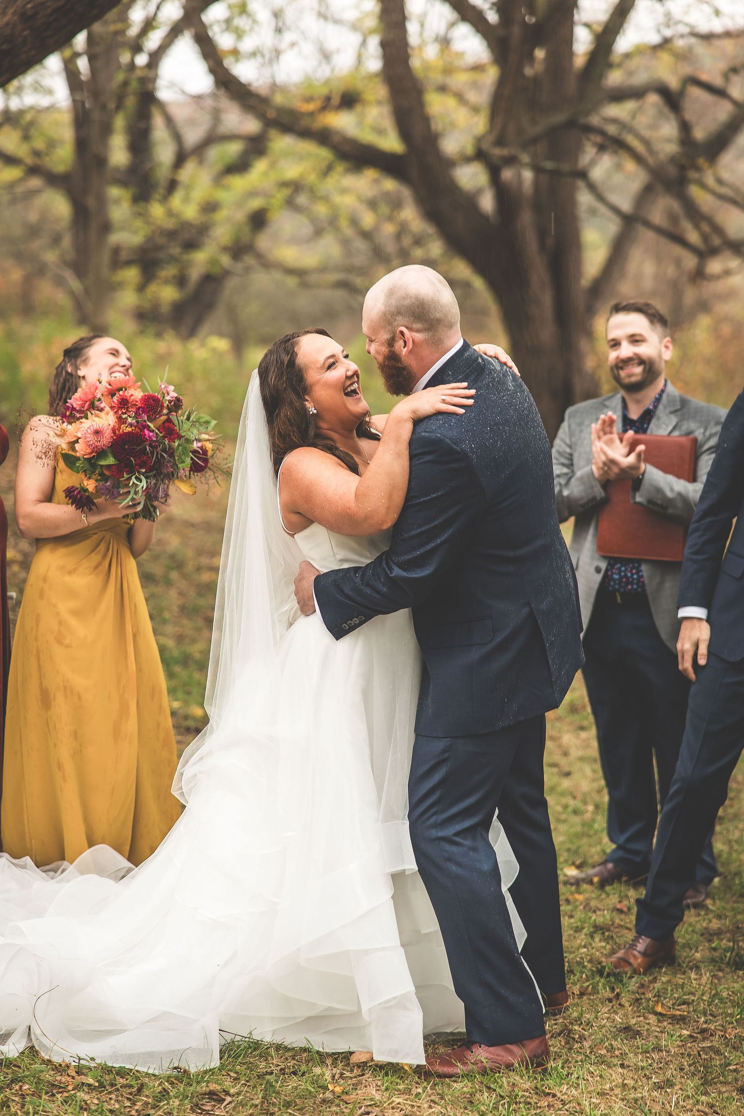 Joyful celebration moment during outdoor autumn wedding with burgundy and gold attire.