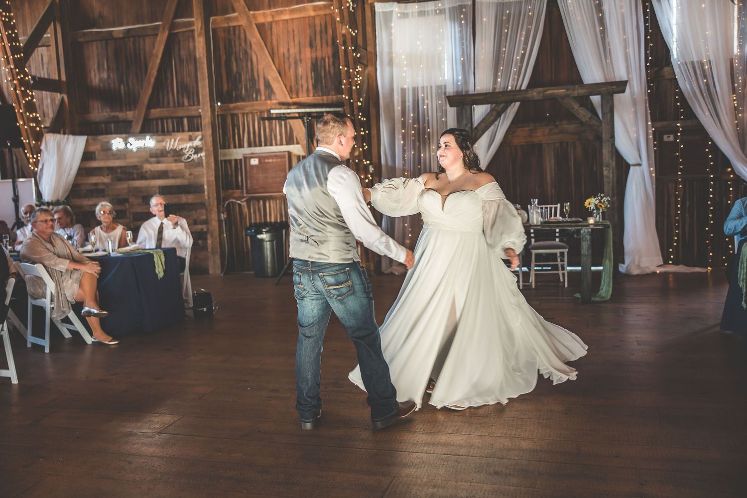 Couples share intimate dances in a rustic barn venue with romantic lighting and decor.