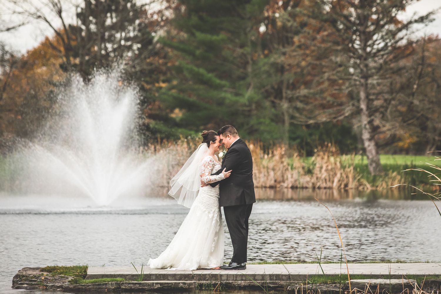 Romantic lakeside portraits with water fountain and autumn scenery.