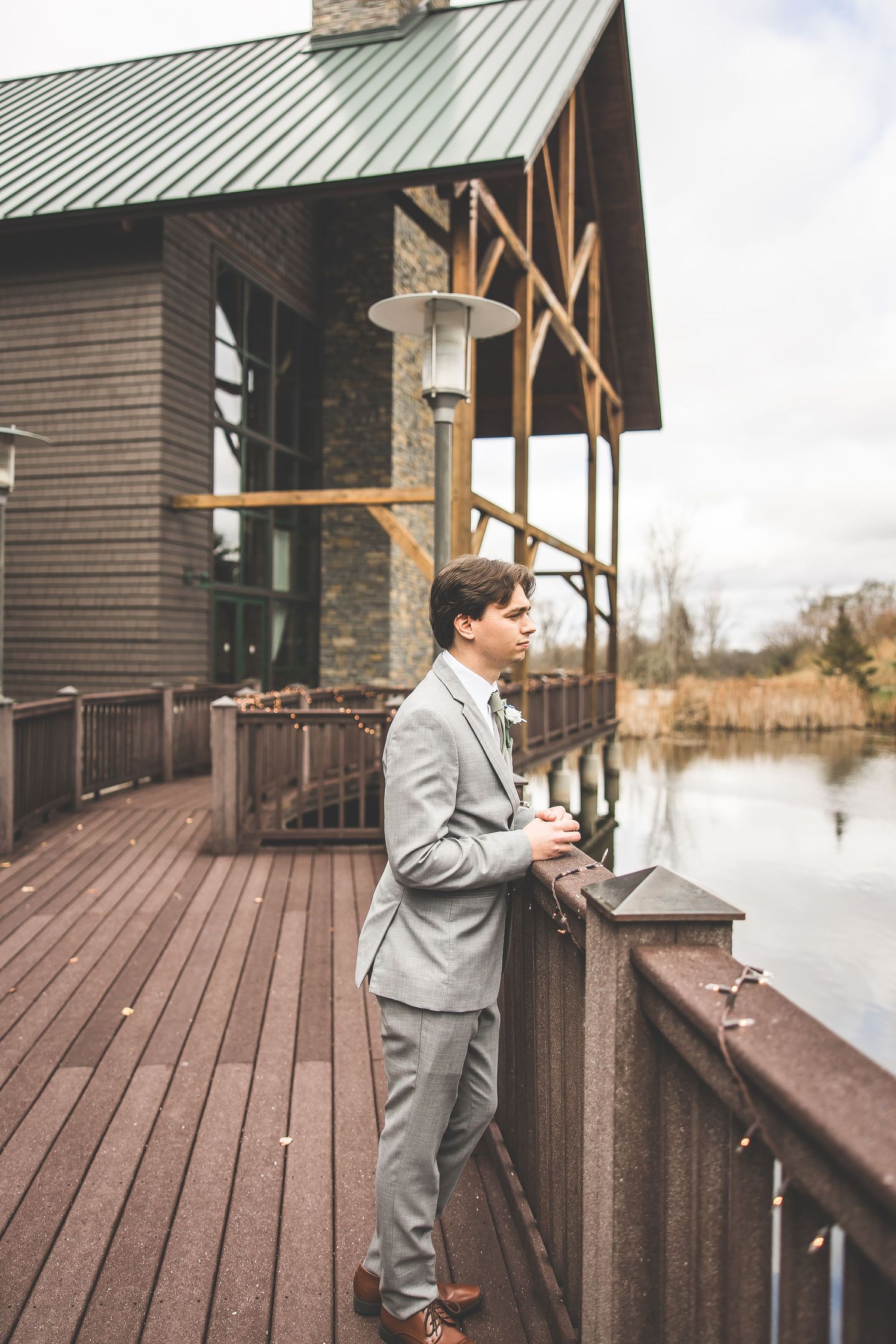 Wedding couple sharing a private moment on a wooden deck overlooking a lake.