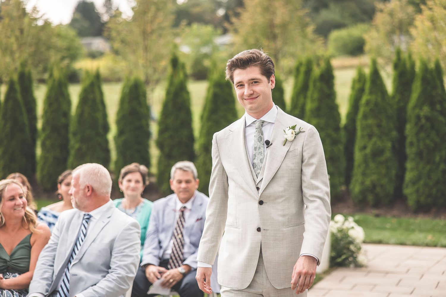 Elegant outdoor wedding ceremony setup with rows of white chairs and decorative floral arrangements.