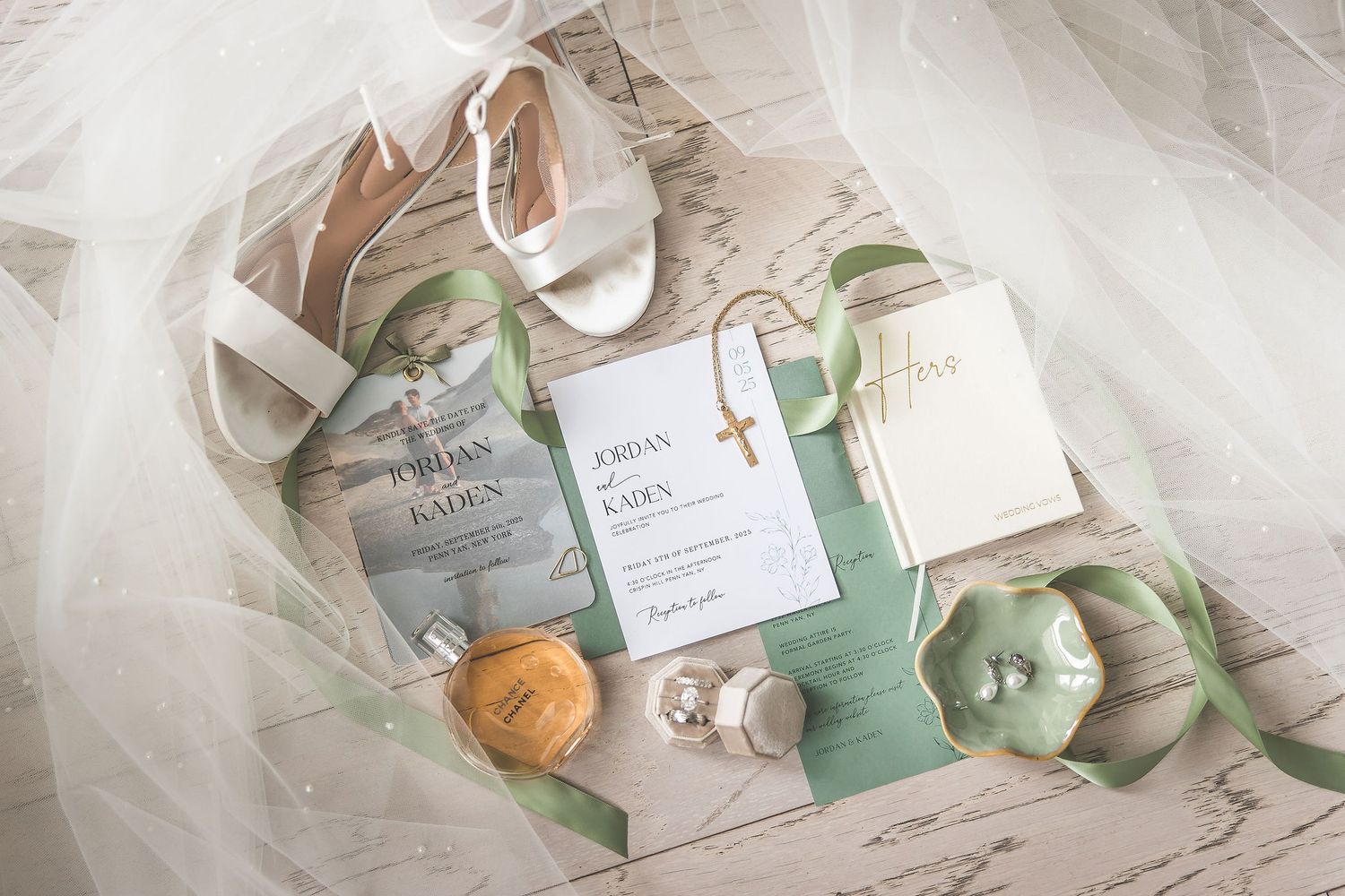 Wedding details including invitations, rings, and floral arrangements laid out on white tulle fabric.