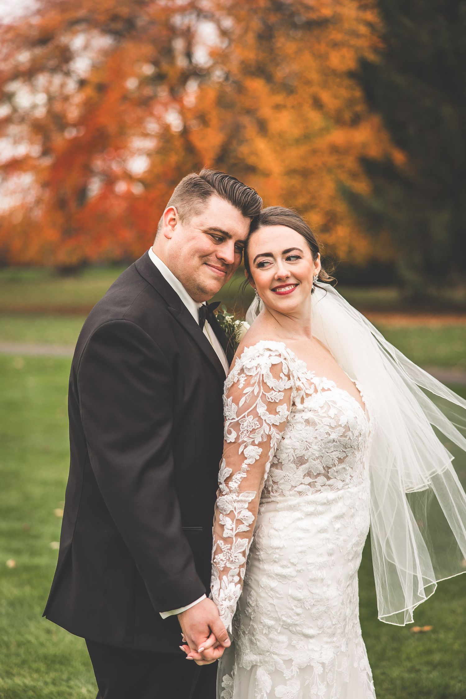 Autumn wedding portraits with vibrant orange foliage in background.