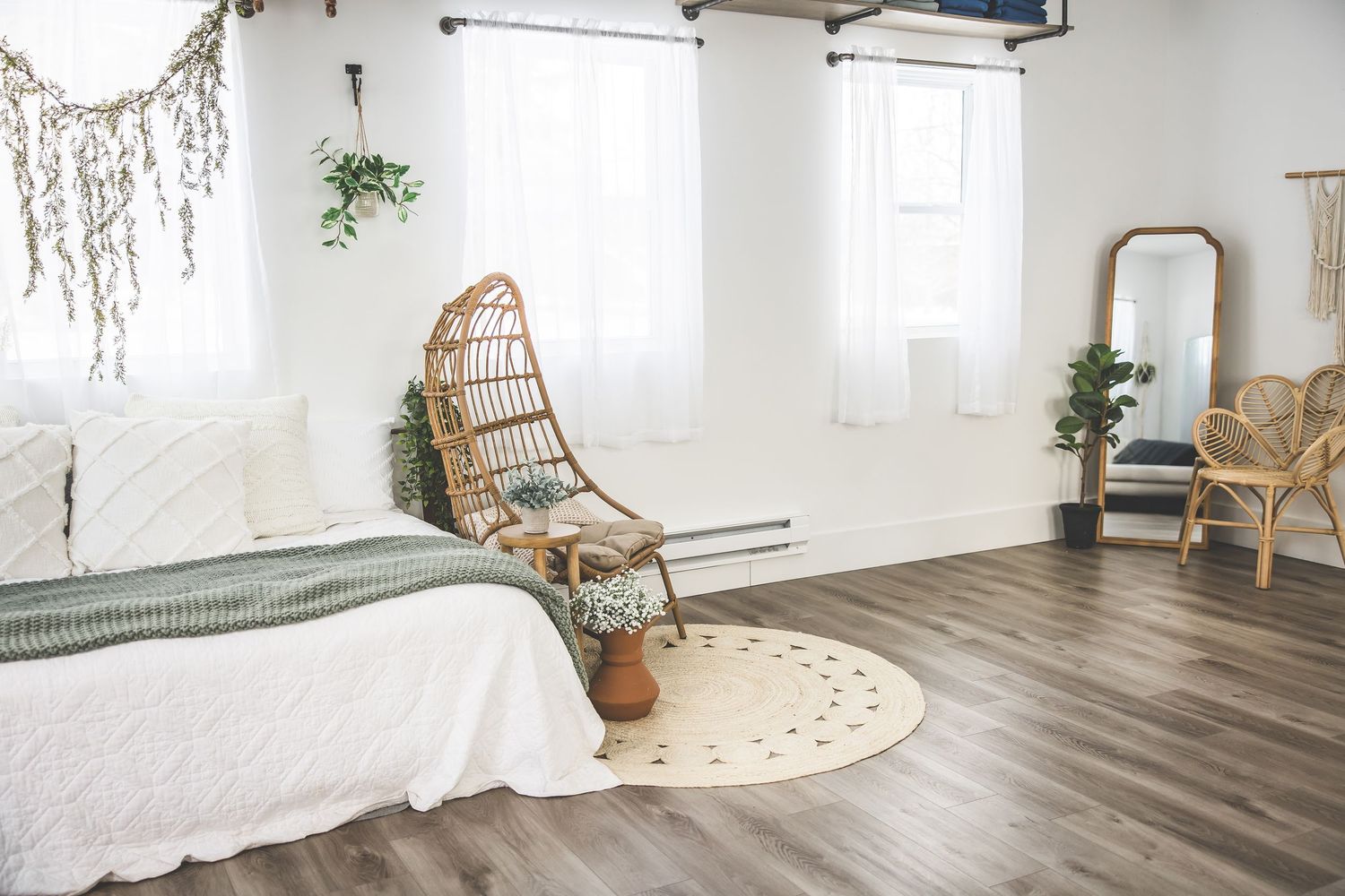 Boho-style studio space with rattan chairs, white walls, wood floors, and natural light from windows.