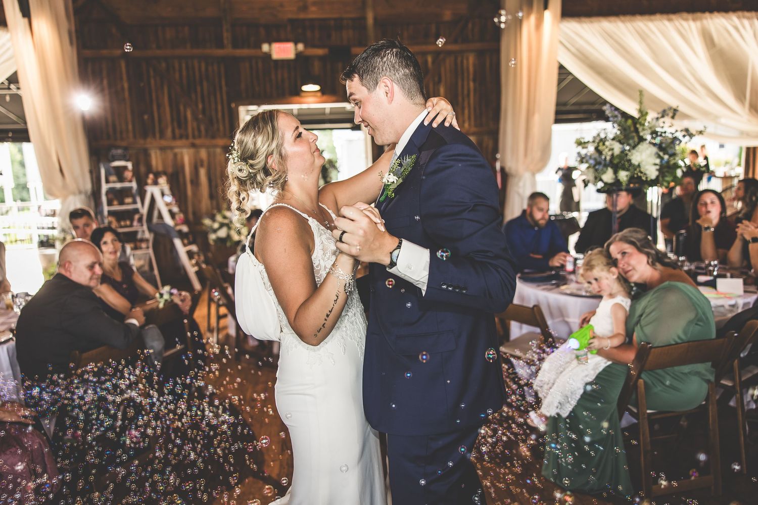 Indoor wedding reception celebration with dancing and confetti in warm lighting.