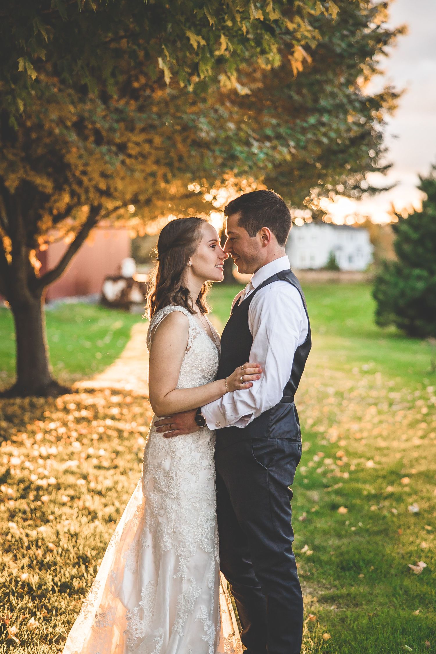 Golden sunset wedding portrait under autumn trees with warm lighting.