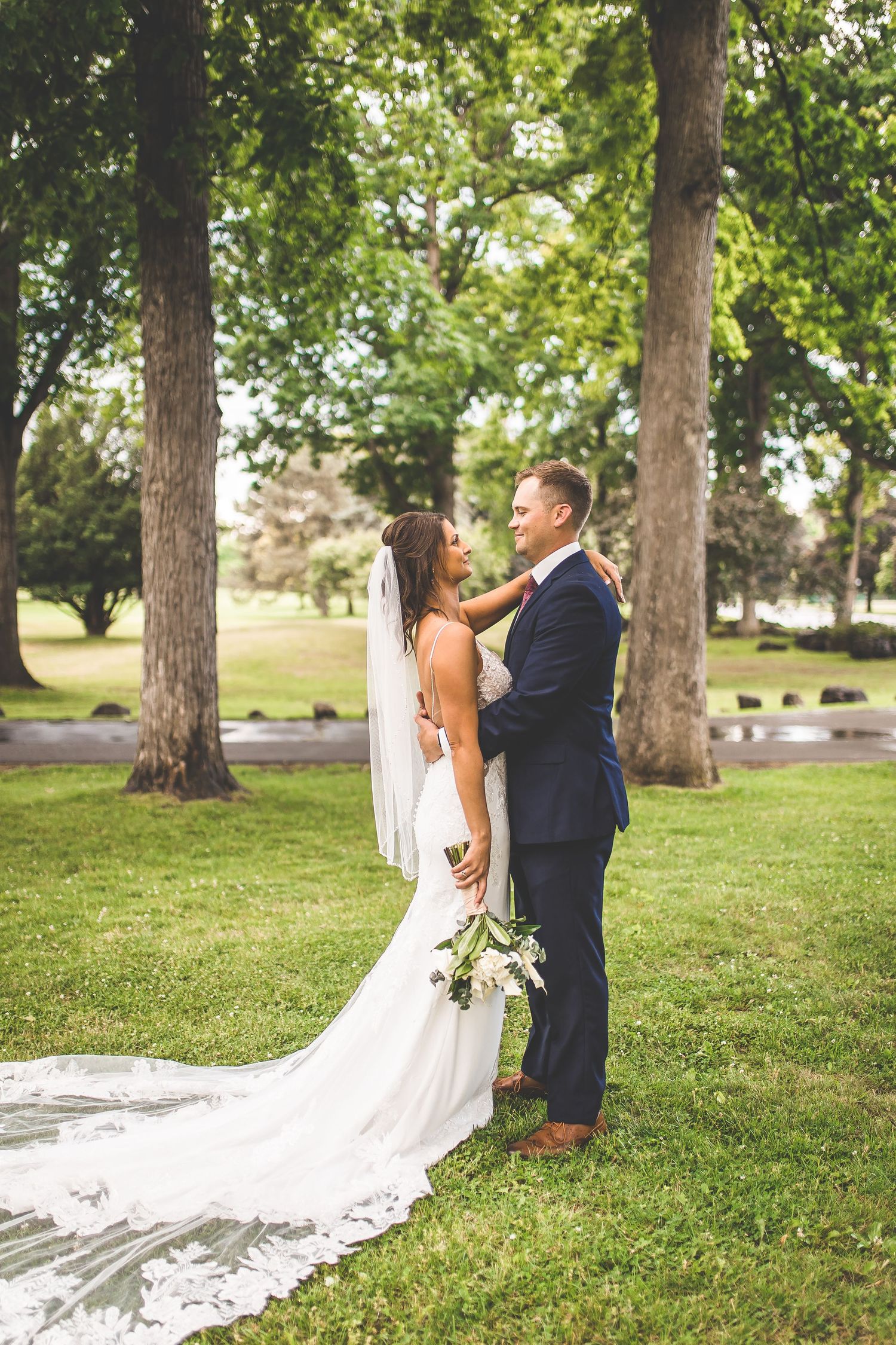 Romantic wedding couple shares intimate moments while posing for photos on grassy lawn.