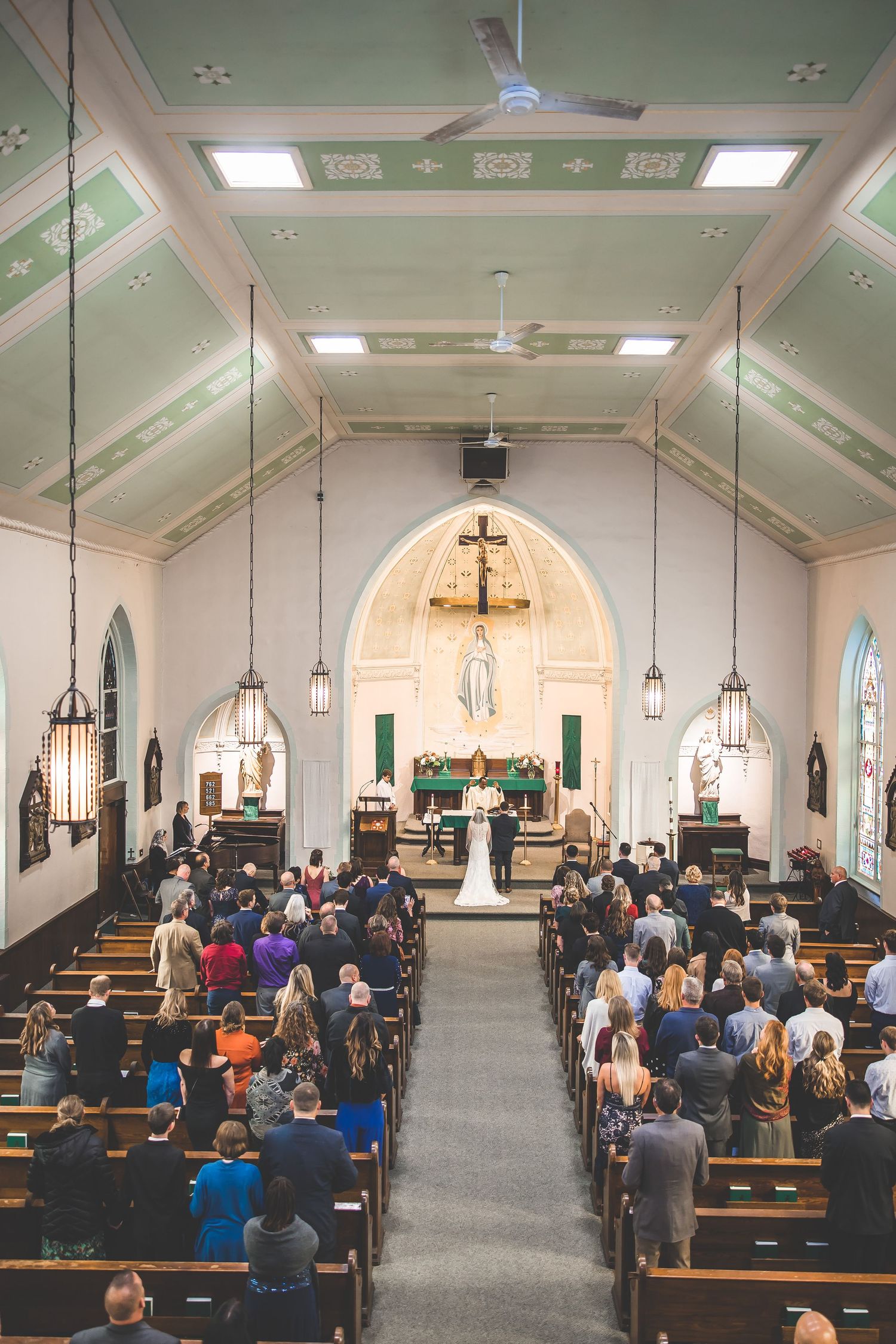 Interior view of a church sanctuary during a wedding ceremony with guests seated in wooden pews.