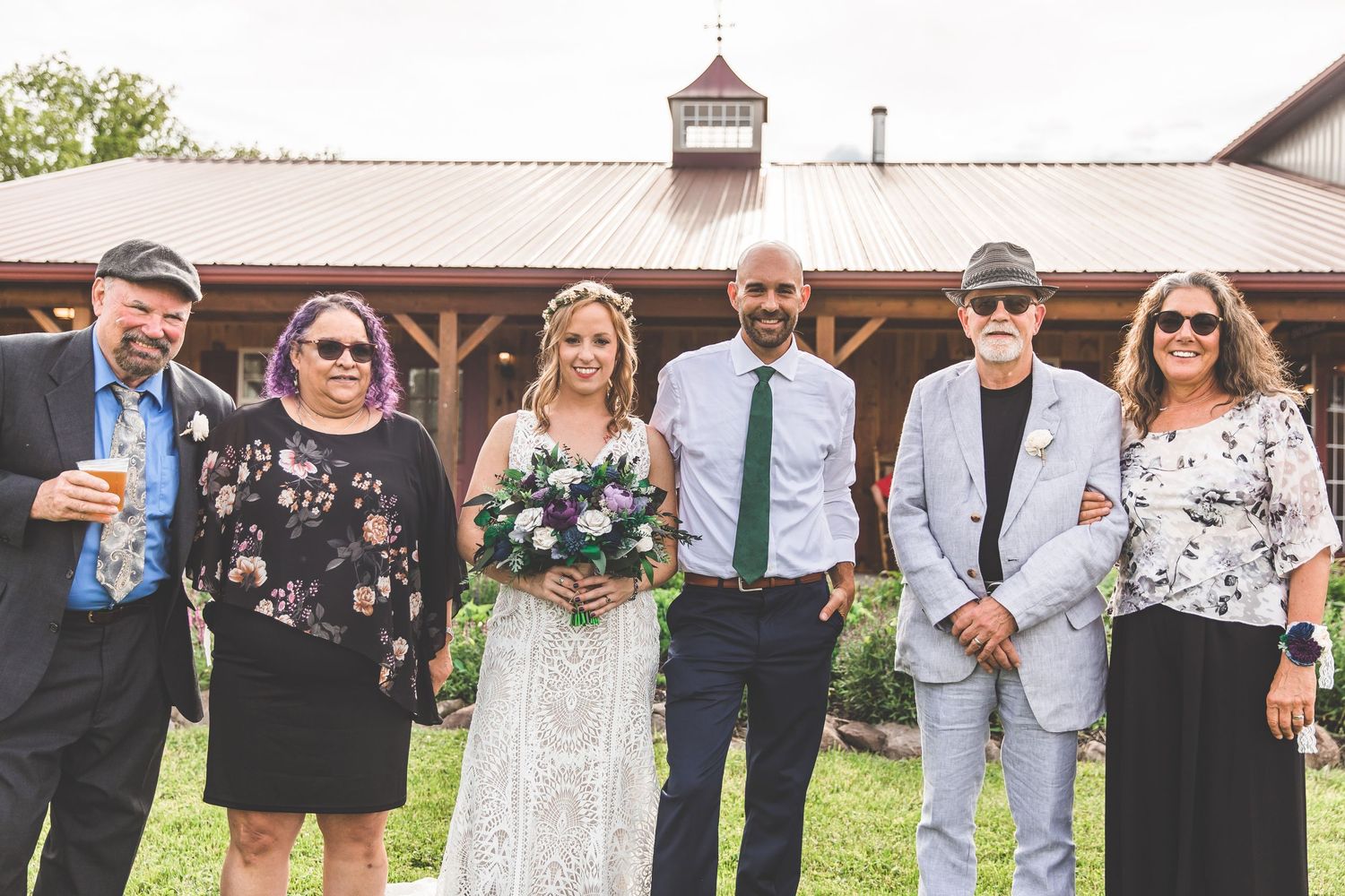 Outdoor wedding venue with rustic barn and wedding party members.