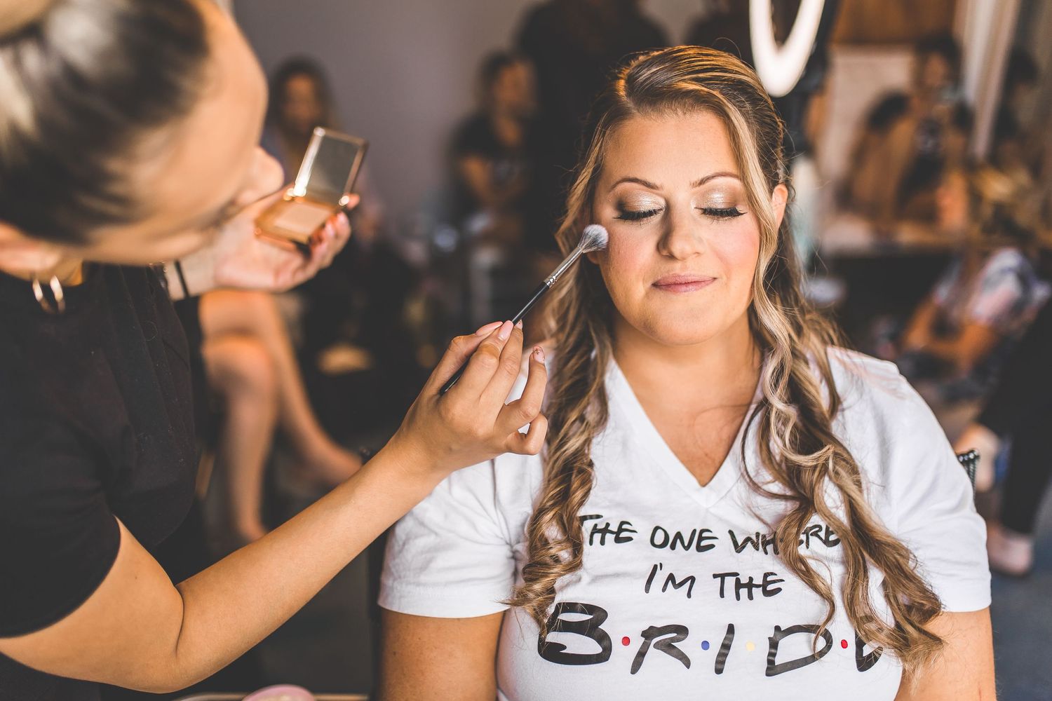Wedding party getting ready with bridesmaids in light blue dresses helping with final touches.