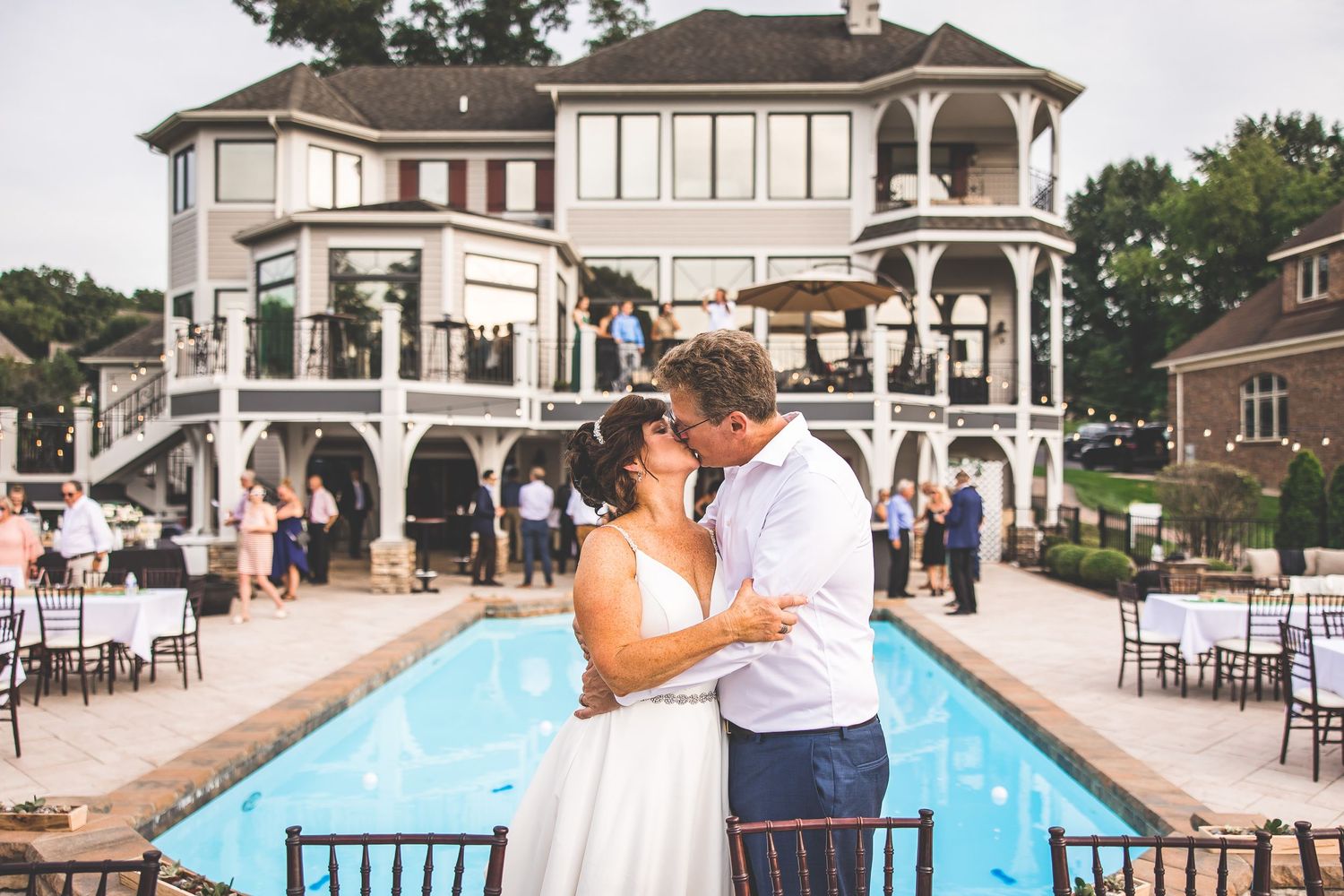 Wedding celebration at an elegant venue with a swimming pool and classical architecture.