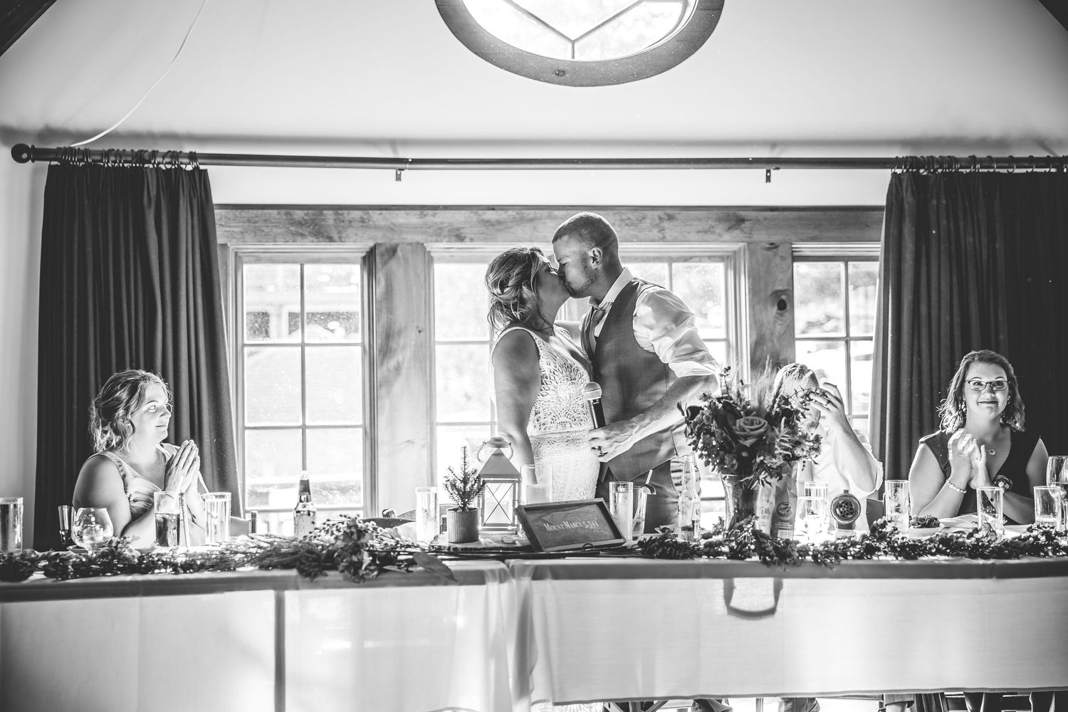 Wide angle black and white shot of an elegant wedding reception space with natural lighting.