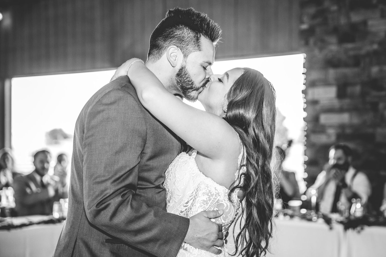 Wedding couple embraces during a romantic dance moment in a rustic venue.