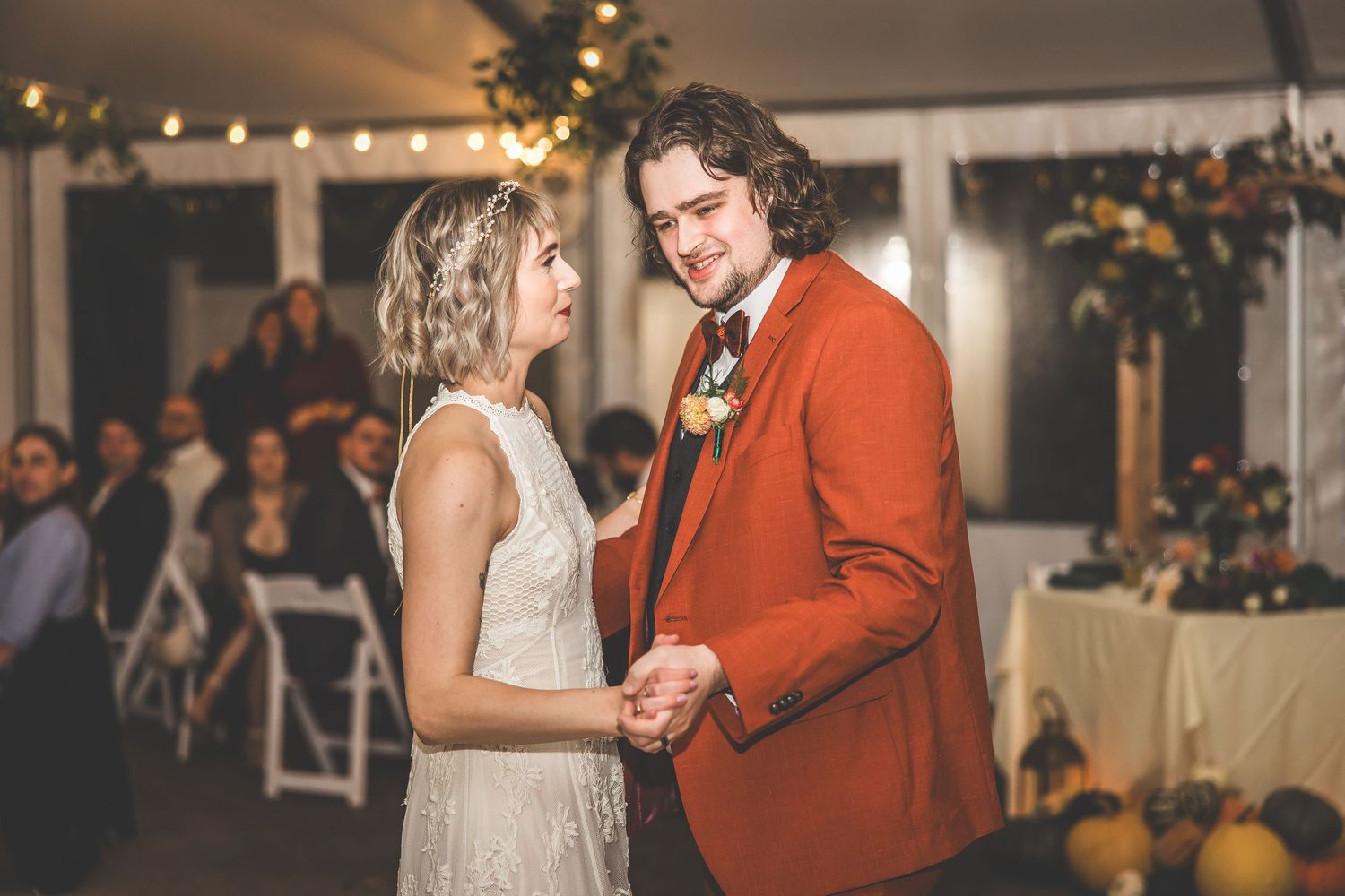 Dancers share a romantic moment on a wooden dance floor at an elegant indoor reception venue.