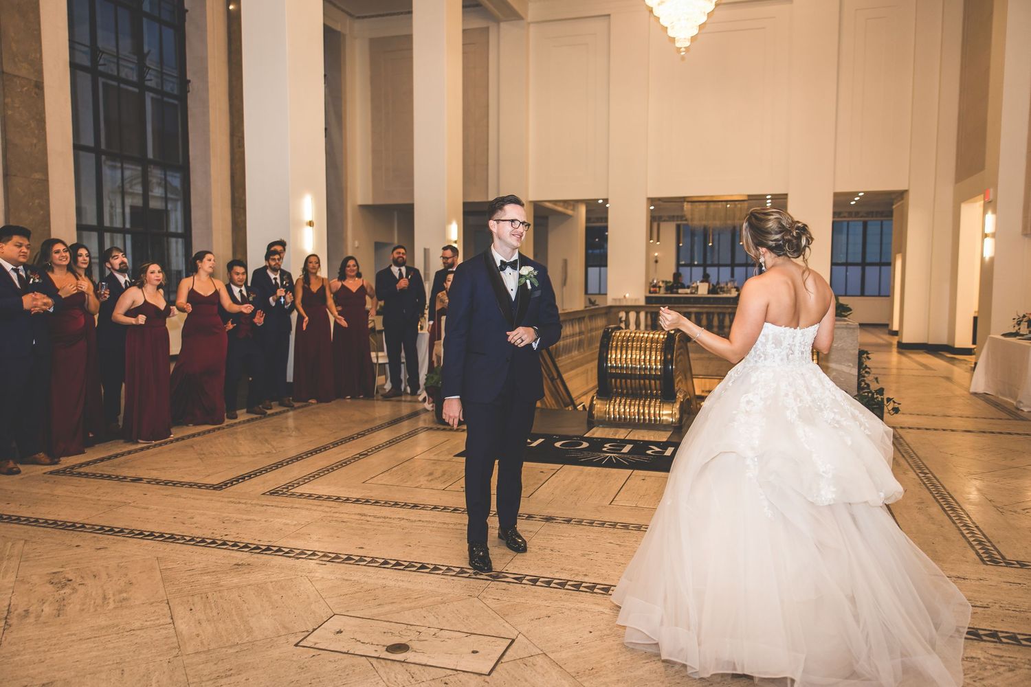 Newlyweds glide across polished ballroom floor during their choreographed first dance.