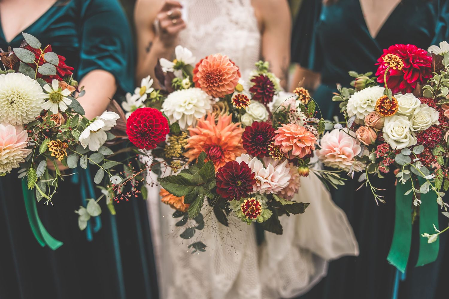 Close-up of autumn wedding bouquets with dahlias, roses, and mixed flowers in rich fall colors.