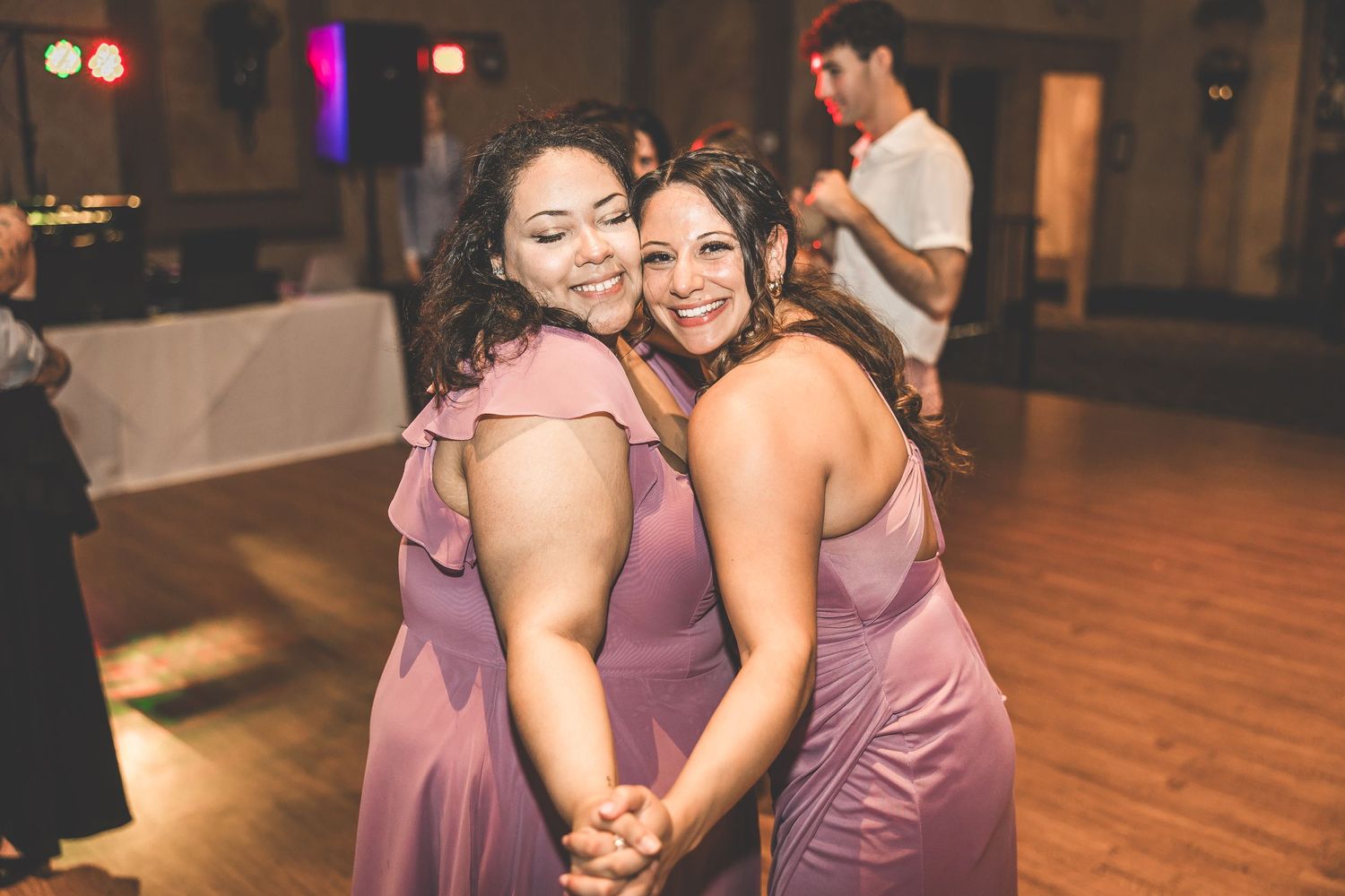 Bridesmaids in mauve dresses dancing together at a wedding reception.