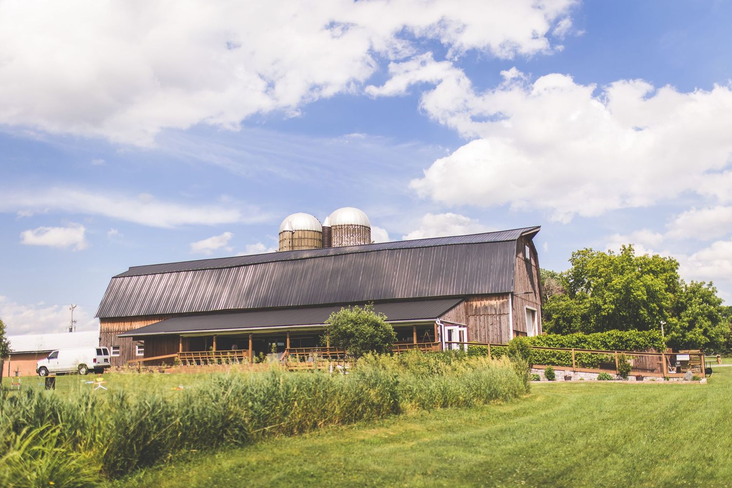 Panoramic view of a countryside wedding venue with barns and rolling hills.