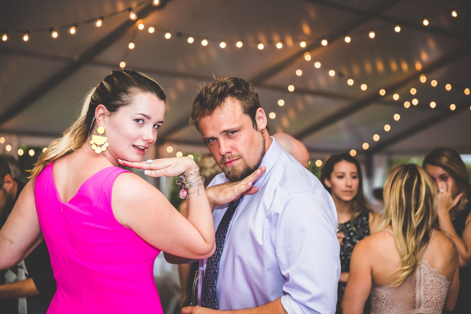 Wedding reception dance party with string lights and guests celebrating.