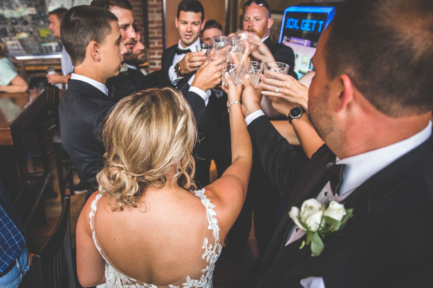 Wedding guests dancing and celebrating on a crowded dance floor at an indoor reception venue.