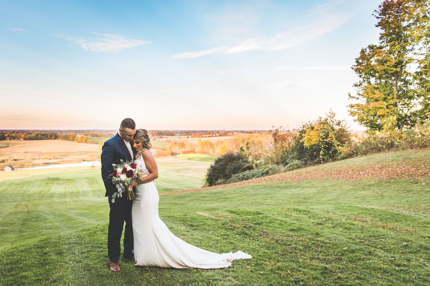 Wedding couple portraits taken in a scenic field during golden hour.