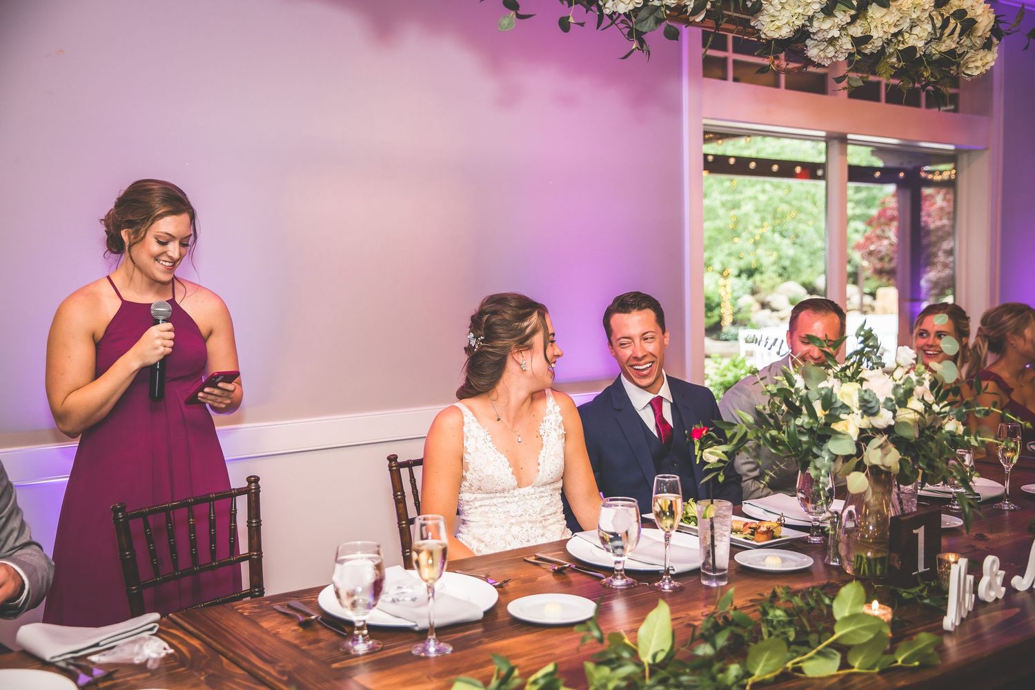 Wedding reception venue decorated with white flowers and purple accent lighting.