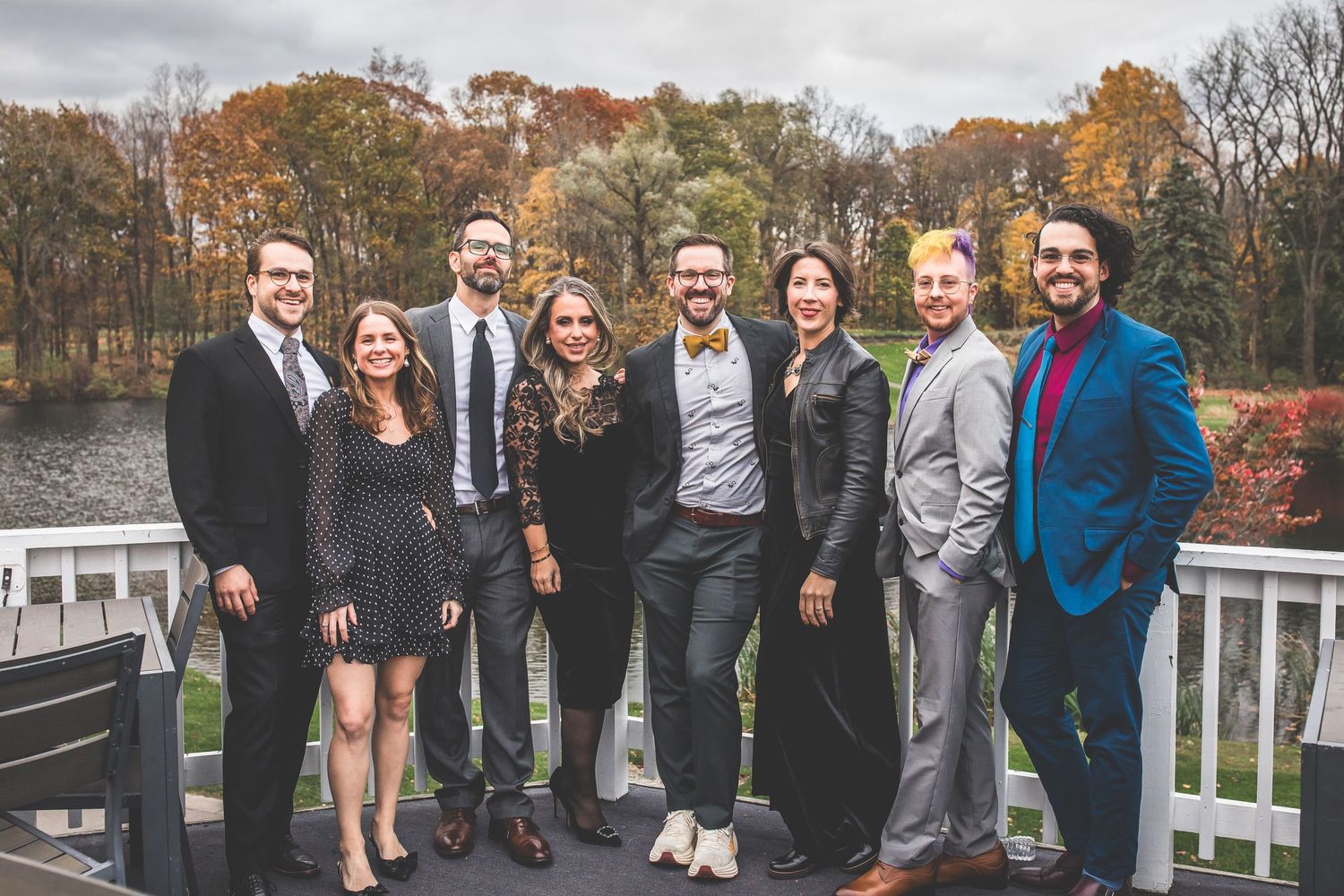 Wedding guests gather on outdoor deck during autumn celebration.