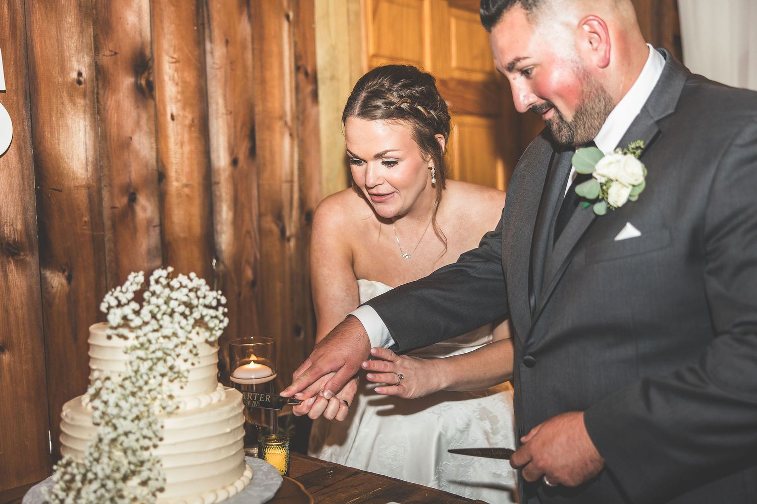 Couple cutting their wedding cake together at rustic barn reception.